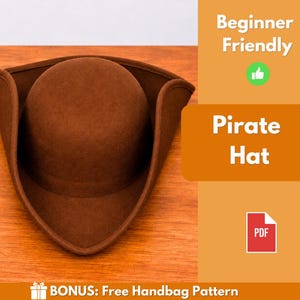 Peut inclure: Un chapeau de pirate en feutre marron avec une calotte arrondie et un large bord retroussé. L'image contient le texte Beginner Friendly, Pirate Hat, PDF, et BONUS: Free Handbag Pattern, ainsi qu'une icône de pouce levé et une icône de document PDF.