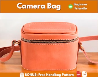 Può includere: Una borsa per fotocamera in pelle color corallo con chiusura a zip e tracolla. La borsa è su una superficie di legno. BONUS: Modello di borsa a mano gratuito PDF DXF
