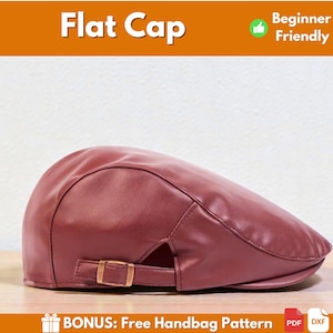 Puede incluir: Gorra plana burdeos con hebilla dorada. La gorra está hecha de un material liso y tiene una visera curva. El texto "Flat Cap" se muestra en la parte superior. También se muestran las palabras "Beginner Friendly".