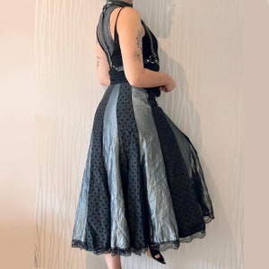 May include: A black and silver polka dot skirt with a black lace trim. The skirt is full and flowing, and it has a high waist.