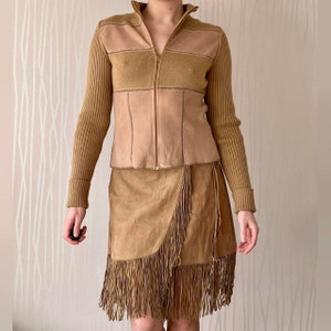 May include: A brown suede skirt with fringe detailing and a brown leather jacket with a zipper closure.