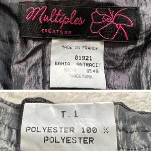 May include: A black and white fabric with a label that reads "Multiples Createur" and "Made in France". The label also includes the text "01921 Bahia Antracit B210 6549 Trademark". A second label reads "T.1 Polyester 100% Polyester".