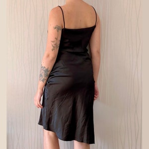 May include: A black satin slip dress with thin straps. The dress has a simple, elegant design and a flowing silhouette.