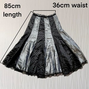 May include: A black and silver skirt with a polka dot pattern and lace trim. The skirt is 85 cm long and has a 36 cm waist.
