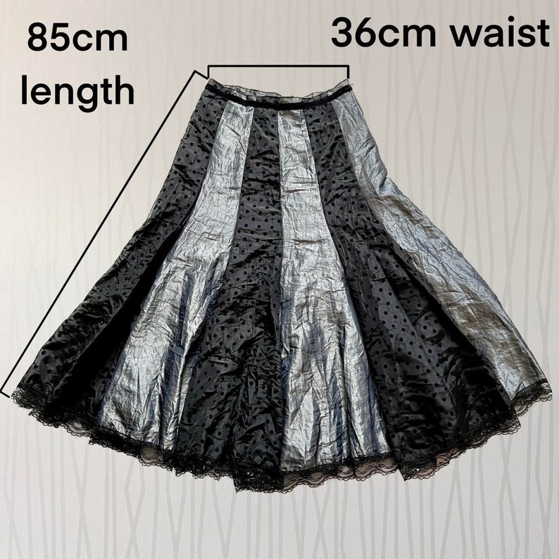 May include: A black and silver skirt with a polka dot pattern and lace trim. The skirt is 85 cm long and has a 36 cm waist.