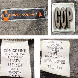 May include: A gray cotton and polyester blend jacket with a label that reads "COP...COPINE NUMERO DE TVA FR 19732043062 PLATA REF: 6134 VESTE 71% COTON 29% PES". The jacket also has a patch with the word "COP" in large letters.