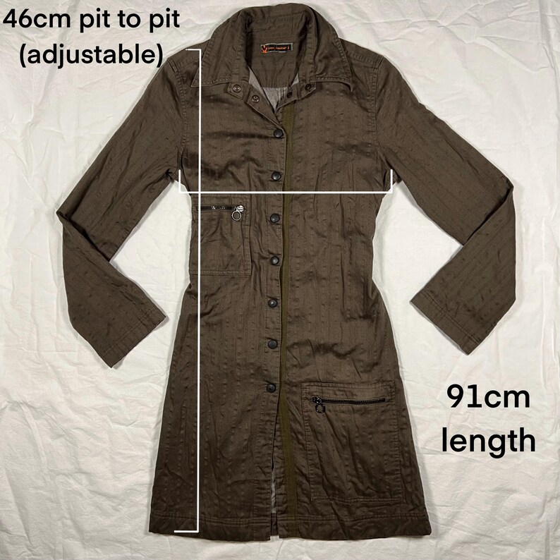 May include: A brown long-sleeved button-up shirt with a collar and pockets. The shirt is 46cm pit to pit (adjustable) and 91cm in length.