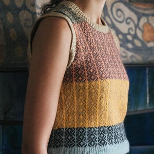 May include: A sleeveless knitted top with a colour block design. The top features a diamond pattern in the upper section, with horizontal stripes of orange, yellow, and blue. The neckline and armholes are trimmed in a neutral colour.