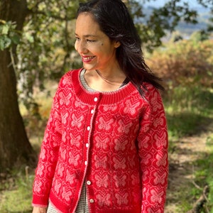 May include: A red cardigan with a pink floral pattern and white buttons. The cardigan is knitted and has a relaxed fit.
