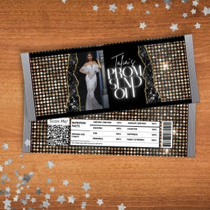 May include: A black and gold invitation card with the text "Talia's PROM SEND OFF". The card features a photo of a person in a white dress and a nutrition facts table. The card is decorated with silver glitter.