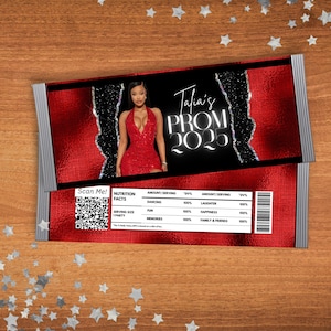 May include: A red and black chocolate bar wrapper with a photo of a woman in a red dress. The wrapper has the text "Talia's Prom 2025" and a nutrition facts label with a QR code.