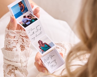 May include: A white, accordion-style photo box with four images and text. The box is open, revealing photos of a couple and a woman. Text reads "I love you with all of my heart" and "Will You Marry Me?"