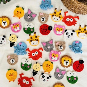 Può includere: Una collezione di applicazioni di facce di animali all'uncinetto colorate, tra cui un leone, un panda, una coccinella e un polpo. Gli abbellimenti fatti a mano sono in vari colori e dimensioni, perfetti per progetti di artigianato.