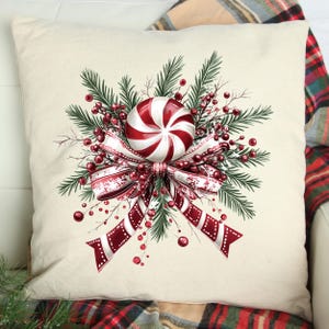 May include: A white throw pillow with a red and white peppermint candy, a red bow, and green pine branches with red berries.