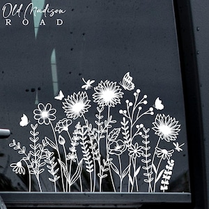 May include: White vinyl decal of a floral design with butterflies and the text "Old Madison Road" on a car window.