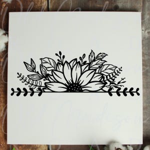 May include: A square white sign featuring a black line art graphic of a large sunflower centered among various leaves and sprigs. A horizontal line extends from the base of the floral arrangement, decorated with a repeating leaf pattern on both sides.