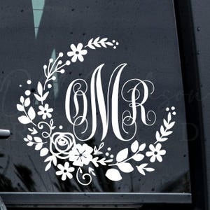May include: White floral monogram decal featuring the letters "OMR" in a decorative script font. The letters are encircled by a wreath of leaves, flowers, and berries, creating a personalized and elegant design.