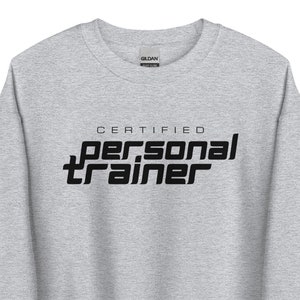 Könnte beinhalten: Ein hellgraues Sweatshirt mit dem schwarzen Aufdruck "CERTIFIED personal TRAINER". Der Text ist in einer fetten, serifenlosen Schriftart gehalten. Das Sweatshirt hat einen Rundhalsausschnitt.