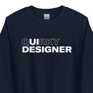 May include: Navy blue sweatshirt with the text "QUIRKY DESIGNER" in white block letters. The sweatshirt is a solid color and has a crew neck. The Gildan brand label is visible at the top.
