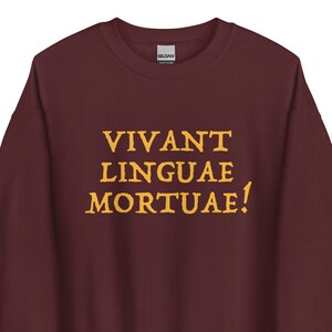 Op de afbeelding: Bordeauxkleurige trui met de tekst "VIVANT LINGUAE MORTUAE!" in geel.