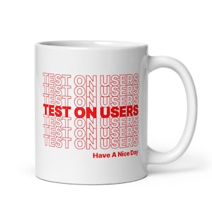 May include: White ceramic mug featuring the repeated text "TEST ON USERS" in red, with one instance in a bolder font. The phrase "Have A Nice Day" is printed in red at the bottom of the mug.