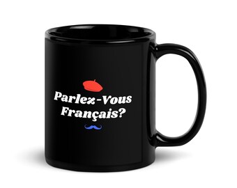 May include: Black ceramic mug with a white text that reads "Parlez-Vous Français?" along with a red beret and blue mustache graphic. The mug has a large handle and a glossy finish.