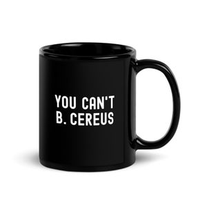 Könnte beinhalten: Schwarze Keramik-Tasse mit weißem Text "YOU CAN'T B. CEREUS". Die Tasse hat einen großen Henkel und eine glänzende Oberfläche. Geeignet für heiße oder kalte Getränke.