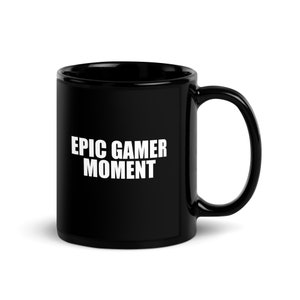 May include: A black ceramic mug with a white inscription that reads "EPIC GAMER MOMENT". The mug has a large handle and a glossy finish. Perfect for enjoying your favorite beverage while gaming.