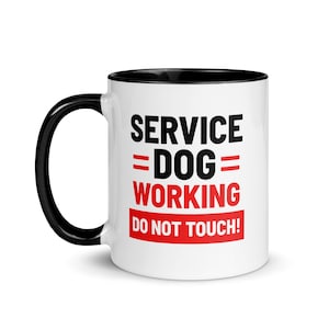 Può includere: Tazza in ceramica bianca con bordo e manico neri. La tazza ha testo nero che recita "SERVICE = DOG = WORKING DO NOT TOUCH!" con le parole "DOG" e "WORKING" in rosso.