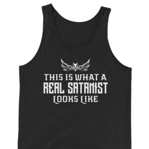 May include: Black tank top with white text that reads "THIS IS WHAT A REAL SATANIST LOOKS LIKE." The text is in a bold, gothic font, with a winged emblem above the text. The tank top is made of a soft material.
