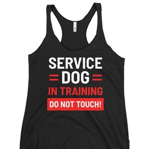 May include: Black racerback tank top with white text that reads "SERVICE DOG = DOG = IN TRAINING DO NOT TOUCH!" The text is in a bold, sans-serif font. The words "IN TRAINING" and "DO NOT TOUCH!" are in a red rectangle.