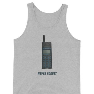 May include: A light gray tank top featuring a graphic of a vintage Ericsson mobile phone. The phone is black and teal with a keypad and antenna. Below the phone, the text reads "NEVER FORGET".