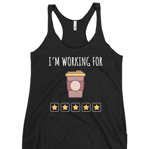 Peut inclure: Débardeur noir avec le texte "I'M WORKING FOR" au-dessus d'une tasse à café de dessin animé et de quatre étoiles dorées. La tasse à café est marron avec un couvercle beige et un cercle rose clair. Le débardeur est en matière douce et confortable.