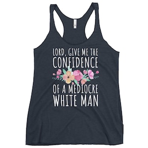 Puede incluir: Camiseta sin mangas de espalda nadadora azul marino oscuro con el texto "LORD, GIVE ME THE CONFIDENCE OF A MEDIOCRE WHITE MAN" en blanco. Un diseño floral con flores rosas y melocotón y hojas verdes está encima del texto.