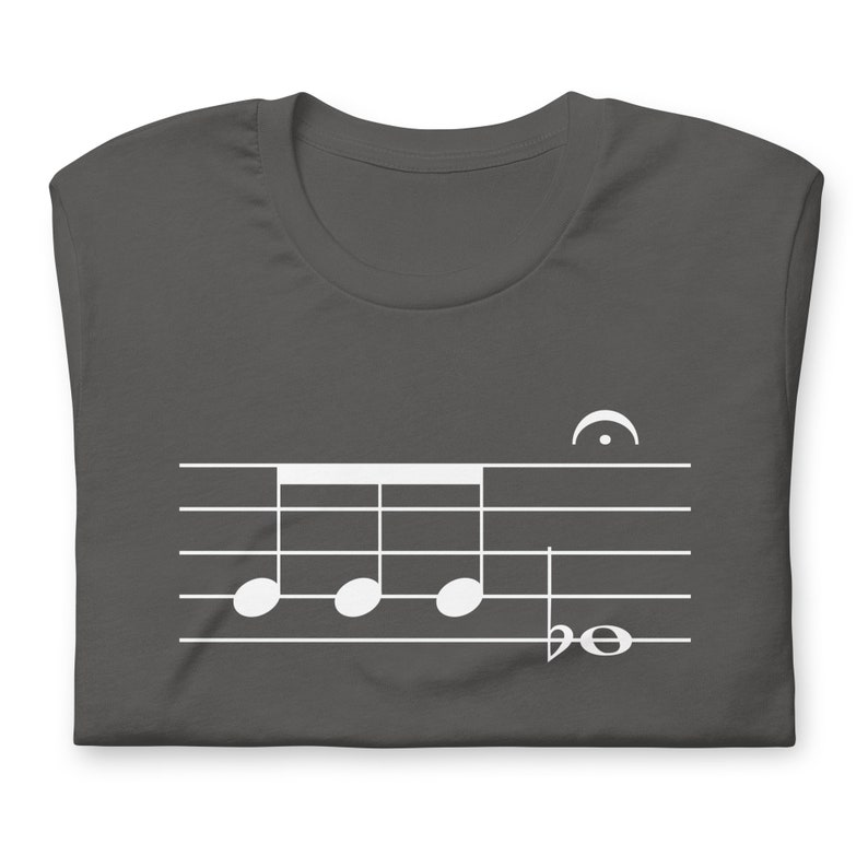 May include: A dark gray t-shirt with a white musical note design. The design features four quarter notes and a bass clef.