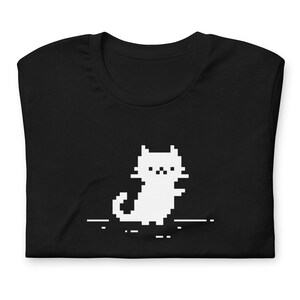 May include: Black t-shirt with a white pixelated cat graphic. The cat is facing forward with its tail curled behind it.