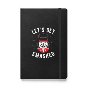 May include: Black notebook with a white design featuring a nutcracker illustration and the text "Let's Get Smashed".