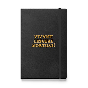 Könnte beinhalten: Ein schwarzes, ledergebundenes Notizbuch mit dem Text "VIVANT LINGUAE MORTUAE!" in goldenen Lettern.