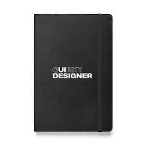 May include: Black leather-bound notebook with a white inscription that reads "QUIRKY DESIGNER".