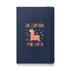 以下が含まれることがあります： カラフルなフォントで「En Español Por Favor」というテキストとラマのイラストが描かれた濃い青色のノートブックです。
