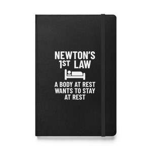 May include: Black notebook with a white graphic that says "Newton's 1st Law" and "A body at rest wants to stay at rest". The graphic also includes a white icon of a bed with a person sleeping in it.