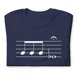 May include: A navy blue t-shirt with a white musical note design. The design features four quarter notes on a staff with a treble clef and a time signature of 4/4.