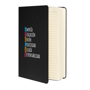May include: Black notebook with lined pages, partially open. The cover features the word "EDUCAR" in colourful letters, with the words "EMPATÍA, DEDICACIÓN, UNIÓN, CREATIVIDAD, ALEGRÍA, RESPONSABILIDAD" stacked vertically.