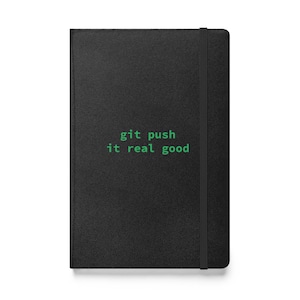Op de afbeelding: Zwart lederen notitieboek met een groene tekstoverlay die "git push it real good" luidt.