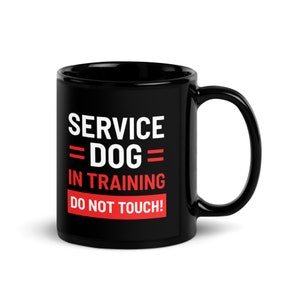 May include: Black ceramic coffee mug with white text that reads "SERVICE DOG IN TRAINING DO NOT TOUCH!" The text "DOG" is in red.