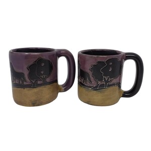 Peut inclure: Deux tasses en céramique violettes avec des silhouettes noires d'arbres et d'animaux. Les tasses ont un glaçage brun sur le fond.