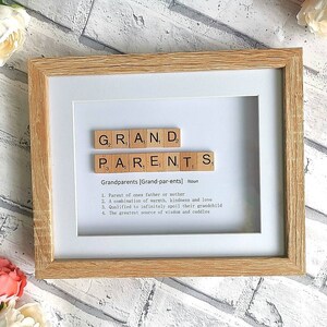 Op de afbeelding: Een ingelijst afdruk met het woord "GROOTOUDERS" gespeld met behulp van houten lettertegels. De definitie van "Grootouders" staat onder de tegels.