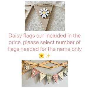 May include: A set of wooden banner flags with a daisy theme. The flags are in beige, pink, and green, spelling "LOTTE". Each flag features a daisy. The flags are connected by twine. The image also contains text.