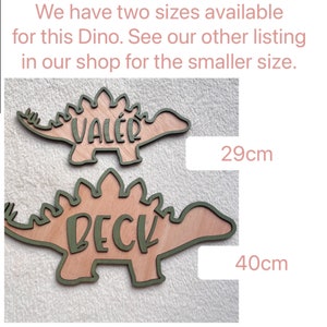 May include: Two wooden dinosaur shapes with names "Val&eacute;r" and "Beck" written on them. The dinosaur shapes are 29 cm and 40 cm in size.
