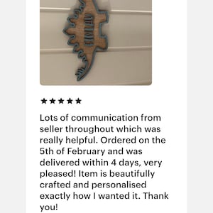 May include: A wooden dinosaur cutout with a blue outline. The dinosaur's name, "FIMLAY", is written on the cutout in a light blue font.